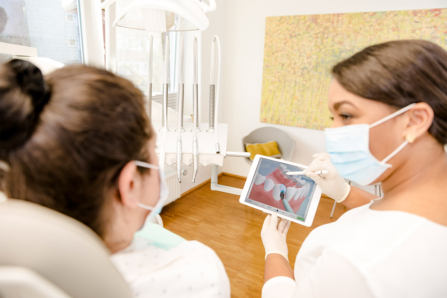 Zahnärztin zeigt Patienten Gebiss auf dem Tablet